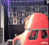 a person sitting in a red chair in front of a wall with pictures on it and the words imgplay at the bottom