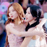 two girls are standing next to each other on a stage and hugging each other .