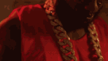 a close up of a man wearing a red shirt and a chain around his neck