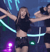 a woman in a black crop top and a black skirt is dancing on a stage