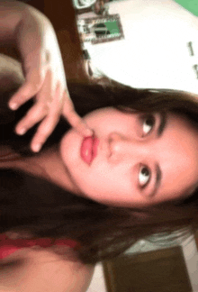 a woman in a red top is making a funny face with her finger in her mouth