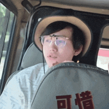 a man wearing a hat and glasses is sitting in a car