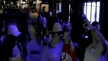 a group of people are standing in a dark room with purple lights