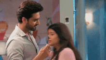 a man is touching a woman 's face while they are standing next to each other .