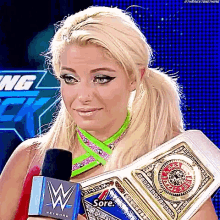 a female wrestler is holding a wrestling championship belt and talking into a microphone .