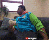 a man is sitting on a couch eating a sandwich with the youtube logo in the background