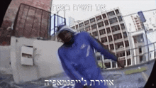 a man in a blue hoodie is dancing in front of a building in hebrew