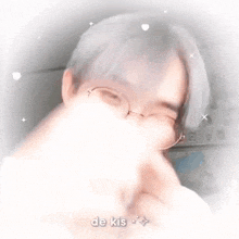 a close up of a person wearing glasses making a heart shape with their hands .