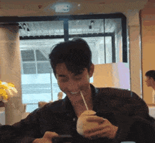 a man drinking from a coconut with a straw and smiling