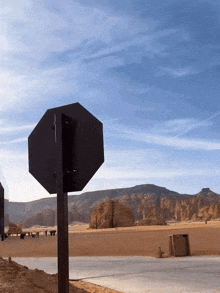 a stop sign in the middle of the desert with mountains in the background