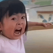 a little girl is making a funny face with her mouth open and her eyes closed .