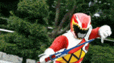 a red and white power ranger is holding a blue sword and giving a thumbs down .