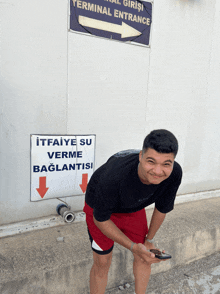 a young man stands in front of a sign that says terminal entrance