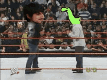 a wrestler with a green dinosaur on his head stands in the ring