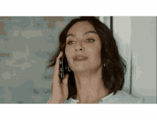 a woman is talking on a cell phone and looking at the camera .