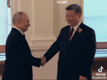 a man in a suit and tie shaking hands with another man in a suit and tie