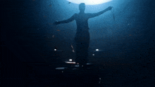 a silhouette of a man with his arms outstretched in front of a drum set