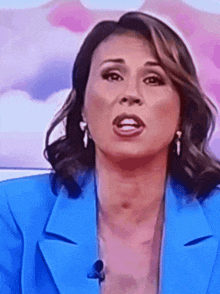 a woman in a blue jacket and earrings is making a face