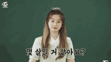 a group of girls are sitting at desks in a classroom with a twice logo on the wall above them