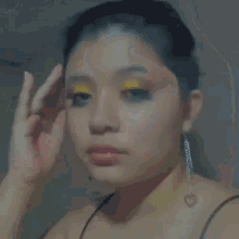a close up of a woman 's face with yellow eye shadow and black eyeshadow .
