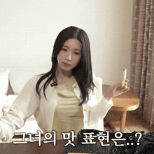 a woman in a white cardigan is holding a cigarette in her hand with korean writing below her