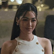 a woman is wearing a white sweater with gold buttons