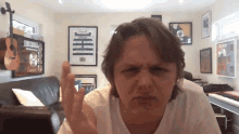 a man is making a funny face in a room with posters on the wall including one that says pop