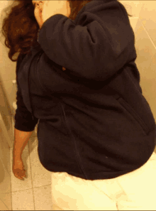 a woman in a black sweatshirt is laying on a toilet