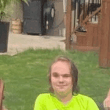a man in a neon green shirt is sitting in the grass with two other people .