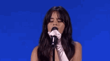 a woman in white gloves is singing into a microphone on a stage .