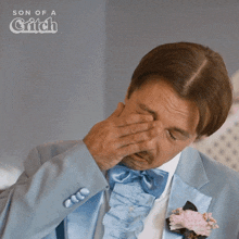 a man in a blue suit wipes his eye with his hand