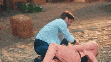 a man is helping a woman who is laying on the ground .