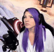 a woman with purple hair is wearing headphones while sitting in front of a microphone