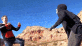 two men are standing next to each other on top of a hill .