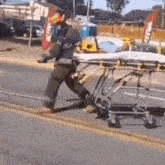 a firefighter is pushing a stretcher down the street .