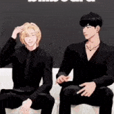 two men in suits are sitting on a couch and one has his hand on his head