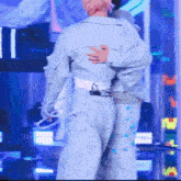 a man in a blue jacket is hugging another man in a white belt