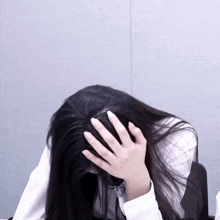 a woman with long hair is covering her face with her hands