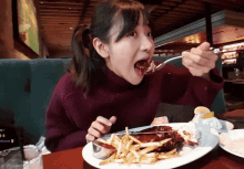 a woman is eating a plate of food with a fork in her mouth