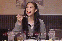 a woman with long hair is sitting at a table with a fork in her mouth .