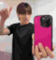 a person is taking a picture of themselves with a pink phone case .