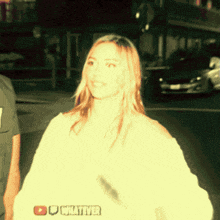 a woman in a white shirt is standing in front of a sign that says whatever