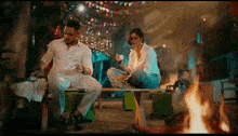 a man and a woman are sitting on a bench with a fire in the background .