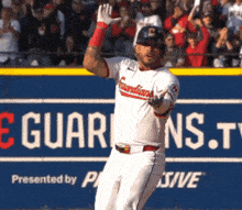 a baseball player is standing in front of a sign that says guardians.tv