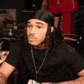 a man with dreadlocks wears a black shirt and a headband