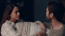 a man and a woman are holding a baby in a bed