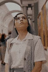 a woman wearing glasses and a white shirt looks up at a painting