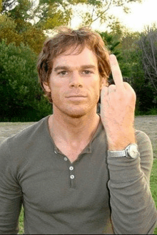 a man in a gray shirt is giving the middle finger .