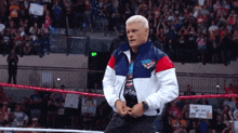 a man in a red white and blue jacket is standing in a ring