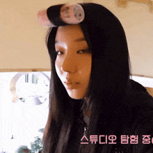 a woman with curlers in her hair has korean writing on the bottom right corner
